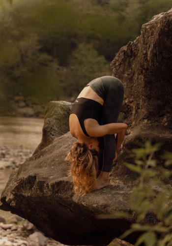 a woman is doing a handstand on a rock